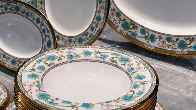 New shiny porcelain plates with gold trim stacked in a dishware shop or crockery store