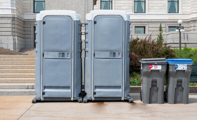 Portable mobile toilets and trash for recycling in the park. A line of chemical WC cabins for a festival event.