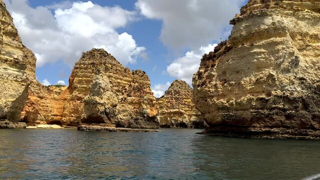 Wide shot showing stunning sandstone cliff formation of algarve during boat trip on atlantic - puffy clouds at sky in background