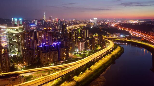 Aerial hyperlapse of Huan Dong Boulevard, an elevated expressway winding along Keelung River in Nangang, Taipei, with landmark 101 Tower in Xinyi Commercial District and busy traffic on the streets