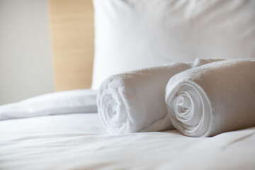 Soft pillows and white towel on clean white bed. Pillows bed with bedding sheets in bedroom. Bed...