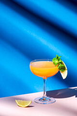 Paddington alcoholic cocktail drink with rum, yellow liquor, grapefruit and lemon juice, marmalade and absinthe, summer blue bright background, hard light and shadows