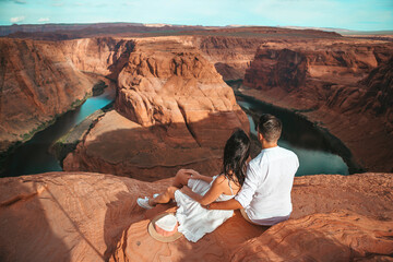Happy couple on the edge of the cliff at Horseshoe Band Canyon in Paje, Arizona. Adventure and tourism concept. Beautiful nature in USA