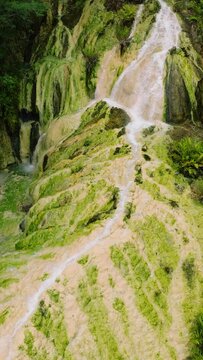 Beautiful hot waterfall in the rainforest. Falls in the tropical mountain jungle. Davao de Oro. Philippines. Vertical view.