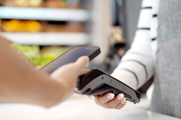 Customer using wireless digital payment on smartphone and credit card at the supermarket or grocery store.