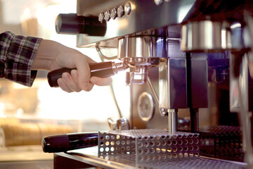 barista making an espresso coffee from the professional espresso machine in coffee shop. Espresso maker machine with portafilter close up.