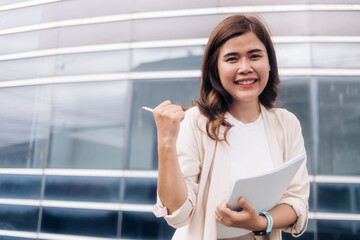 Portrait of happy businesswoman holding document and pen in the city