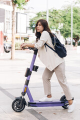 portrait of young asian woman riding electric scooter in park