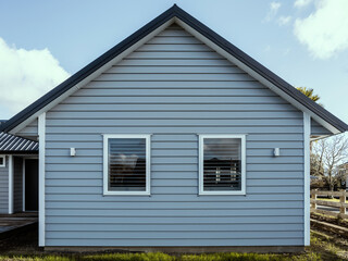Gray suburban house with overlapping wood siding and gabled metal roof. Front view.
