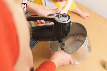 Closeup Mother and her little boy hands making cream for cupcakes, Using electric mixer. Cooking, Homemade.