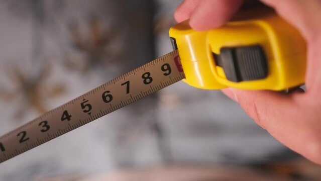 Metal industrial construction tape centimeter measure close up. Male hands pull the measuring tape out of tape measure. Measure the length or width dimensions.