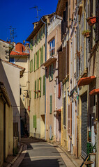 Fototapeta na wymiar Narrow road between traditional old houses on a street near the local covered provencal farmers market in old town or Vieil Antibes, South of France