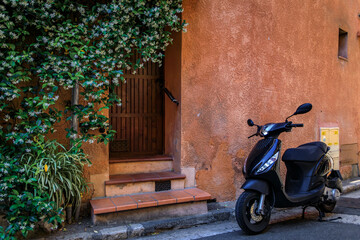 Scooter leaning against a traditional old house by the local covered provencal farmers market in the old town or Vieil Antibes, South of France