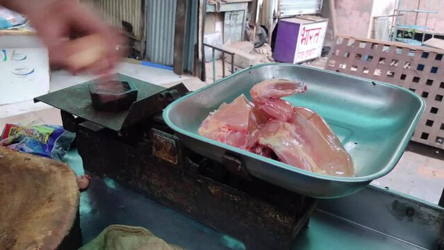 A butcher puts raw chicken breasts on a plate on a weighing scale to prepare delicious food at home. Homemade cooking concept.