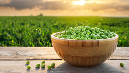 green peas in bowl on wooden table against the agricultural field on sunset
