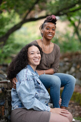 A happy Black, multiracial lesbian couple poses for a portait in a garden.