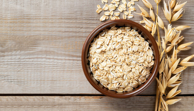 oat flakes in bowl and ears on wooden table top view. Uncooked oatmeal
