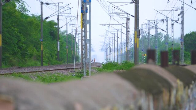 People dangerously crossing railway tracks in India with Electric Lines on top