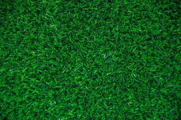 The texture of green artificial grass.Covering for sports stadiums and decorations.