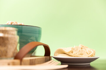 Classic hummus on a small plate on wooden table. Green Background.