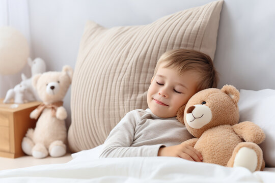 Cute little boy sleeping with teddy bear in bed at home