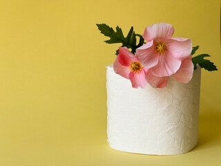 Toilet paper and a flower on a yellow background. Hygiene