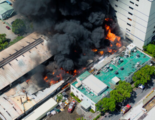 Aerial view of Fire in industrial building. Multi-storey concrete hangar with flames. Factory...