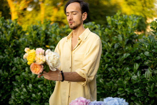 Man arranges a bouquet with cut flowers in garden. Male florist works in his garden outdoors