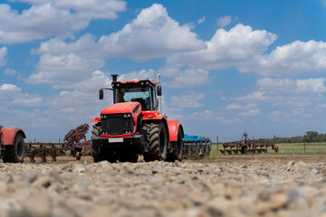 Fototapeta premium Panoramic view of a red wheeled tractor on a farm. Mechanization of agricultural work