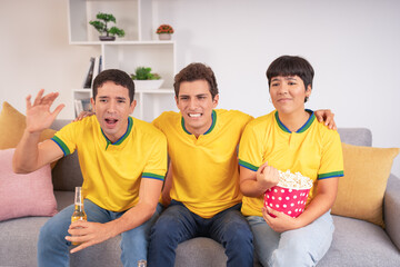 Three friends excitedly watching Brazil on TV