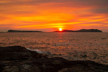 Obraz premium Long exposure of bright orange sunset sky over rippling sea in evening time