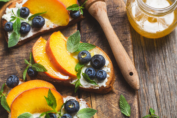White bread sandwich with peaches, blueberries on a wooden board