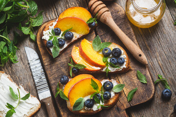 White bread sandwich with peaches, blueberries on a wooden board