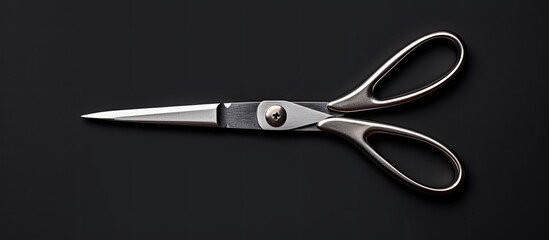 Photo of a pair of scissors on a black surface with ample copy space with copy space - obrazy, fototapety, plakaty