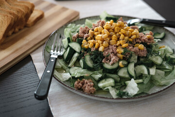 light summer salad with tuna fish, sweet corn, lettuce leaves, cucumber