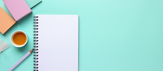 Photo of notepad, pencils, and coffee on turquoise background with plenty of space for text or design with copy space