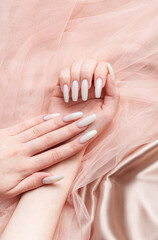 A woman's hands with a manicure on them, the nails are painted in a white color.