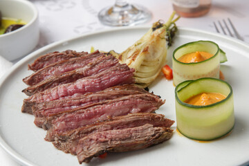 Delicious cuts of medium rare beef tenderloin with with herbed steak sauce served on the restaurant table