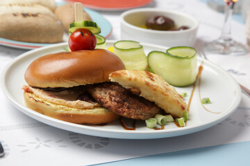 Fine casual dining: classic burger with cucumber slices served on the restaurant table