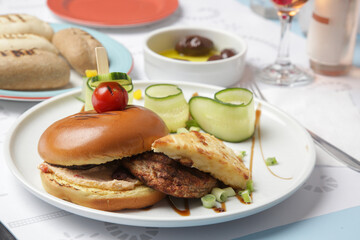 Fine casual dining: classic burger with cucumber slices served on the restaurant table