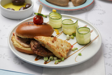 Fine casual dining: classic burger with cucumber slices served on the restaurant table