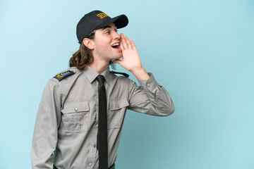Young safeguard man isolated on blue background shouting with mouth wide open to the lateral