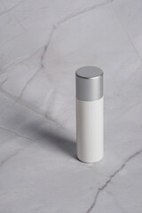 Plastic white tube for cream or lotion. Skin care or sunscreen cosmetic on grey concrete background.