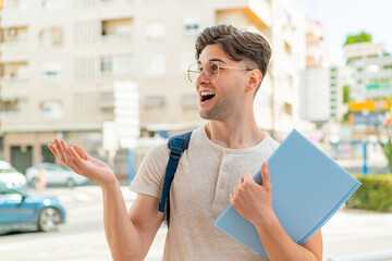 Young handsome student man at outdoors with surprise facial expression