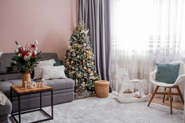 New Year holidays 2023. Cozy decor in gray-green tones in the interior of the Christmas room, a Christmas tree decorated with garlands, gifts, a wooden horse. A festive living room in the house.