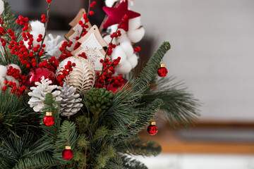 Spruce bouquet with red berries, toys and cotton close-up. Christmas decorations in the interior. The concept of preparation for the New Year holidays in 2024.