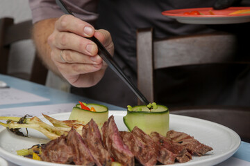 Chef in restaurant decorating dish, close up. Chef preparing meal for serving.