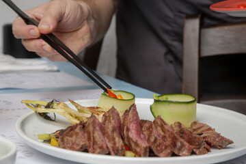 Chef in restaurant decorating dish, close up. Chef preparing meal for serving.