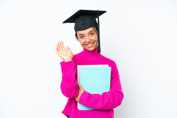 Young student hispanic woman holding a books isolated on white background saluting with hand with happy expression