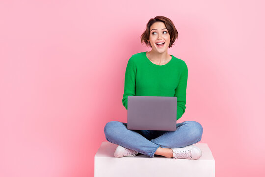 Full length photo of shiny excited lady wear green pullover working gadget looking empty space isolated pink color background